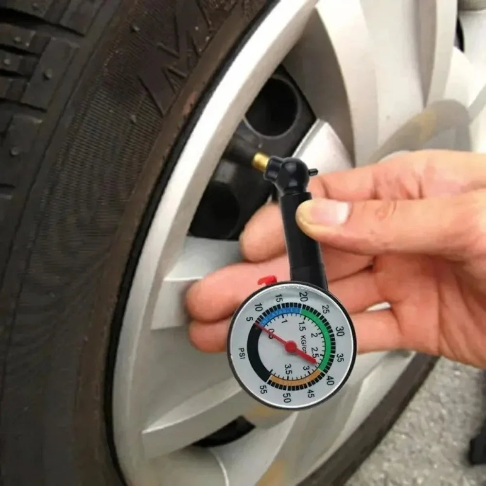 Analog Tire Pressure Gauge - Hand holding dial tire pressure gauge on car tire valve stem during pressure check | Wrench Haus