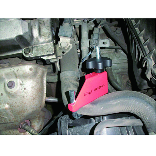 Pink tool with black handle attached to a vehicle's undercarriage | Wrench Haus
